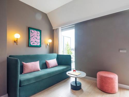 a living room with a green couch and a pink stool at Numa Lisbon Rato in Lisbon