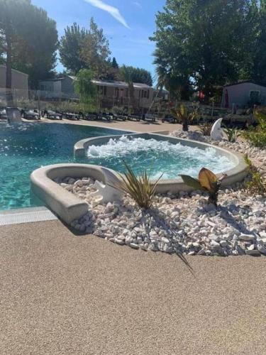 un oiseau debout sur des rochers à côté d'une piscine dans l'établissement Mobil-home 6 personnes valras-plage camping 4 étoiles, à Sérignan