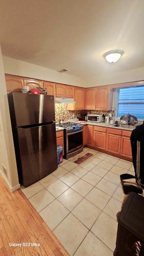 a kitchen with a stainless steel refrigerator and wooden cabinets at Divine Villa and Resort - 32 Evergreen in Newark