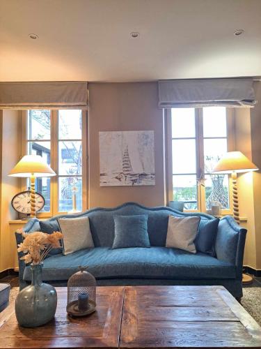 a blue couch in a living room with a table at Hôtel Traiteur Les Ormes, The Originals Relais in Barneville-Carteret