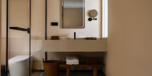 a bathroom with a sink and a toilet and a mirror at Huangshan Yixian Pumanmanju Hotel in Huangshan