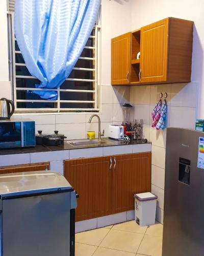 cocina con armarios de madera y cortina azul en Monalisa Homes, en Kampala