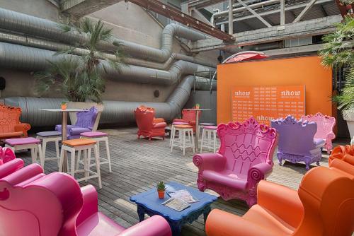 a patio with colorful chairs and tables and pipes at Nhow Milan in Milan