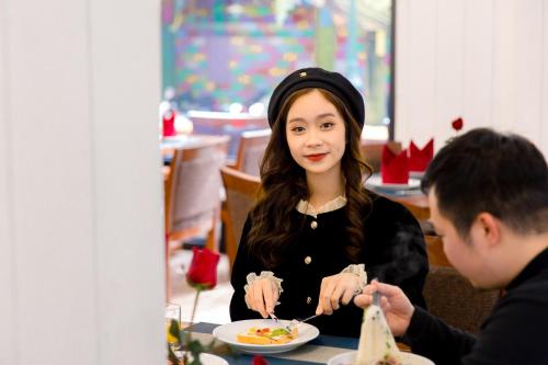 a woman sitting at a table with a plate of food at Babeeni Family Hotel Sapa in Sa Pa