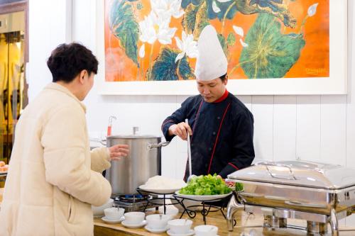 a man and a woman in a kitchen preparing food at Babeeni Family Hotel Sapa in Sa Pa