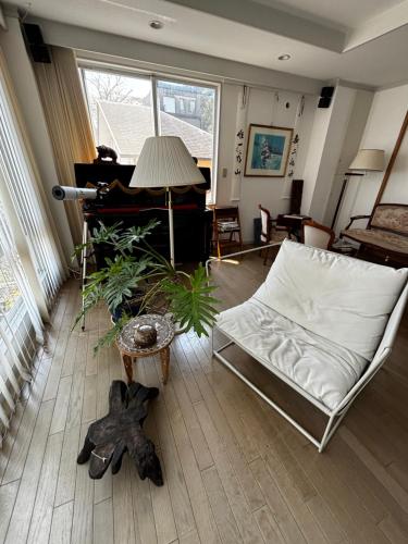 a living room with a white couch and a piano at 熱海 無二荘 絶景オーシャンビュー ピアノ Bbq 三階建て貸切宿 in Atami