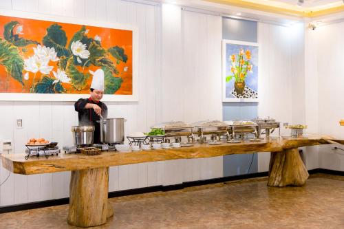 a chef standing in a kitchen with a counter with food at Babeeni Family Hotel Sapa in Sa Pa