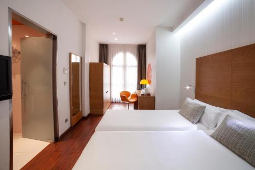 a hotel room with two beds and a window at Petit Palace Plaza Málaga in Málaga