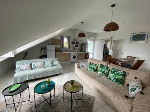 a living room with couches and tables and a kitchen at Le chant du Lagon in La Saline les Bains