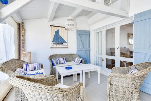 - un salon avec des chaises en osier et une table blanche dans l'établissement Maison pour 8 - 100 m de la plage - Jardin, à La Guérinière