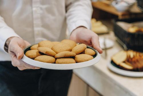 a chef is holding a plate of cookies at Hotel Corsica & Spa Serena in Calvi