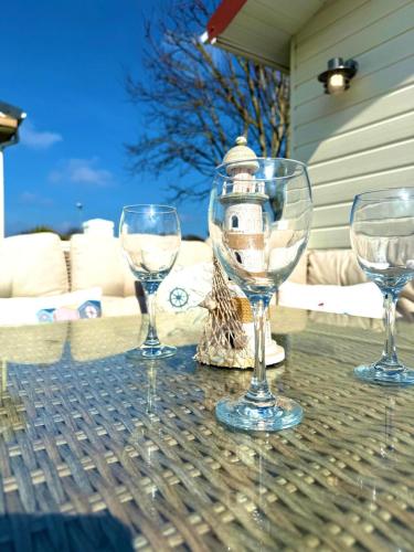 four wine glasses sitting on a table with a lighthouse at Carol's Chalet in Bridlington