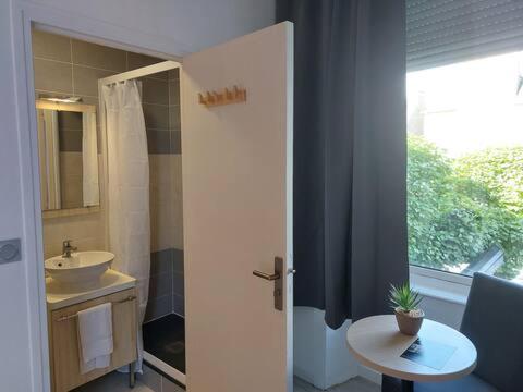 a bathroom with a sink and a toilet and a window at MillSaveurs in Dinan