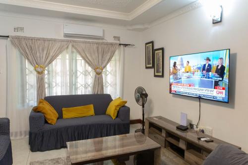 a living room with a couch and a flat screen tv at Elegant Bon Vivant Residence in Livingstone