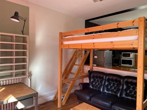 - un lit en mezzanine dans un salon avec un canapé dans l'établissement Studio avec terrasse, salle d'eau et WC partagés, à Lorient