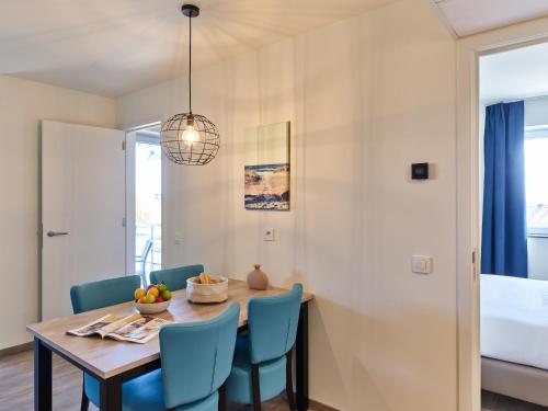 a dining room with a table and blue chairs at Holiday Suites Zeebrugge in Zeebrugge