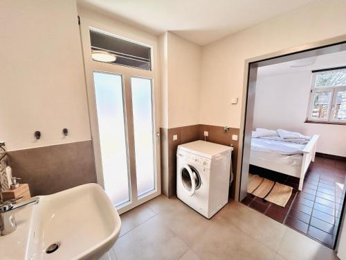 a bathroom with a washer and dryer and a bed at Kuckucksnest - Ferienwohnung mit Traumblick im Schwarzwald in Bad Wildbad