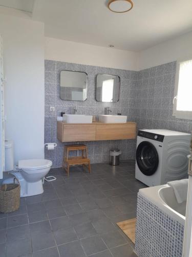 une salle de bain avec un lavabo et une machine à laver dans l'établissement Maison de famille au cœur du bocage normand, à Besneville