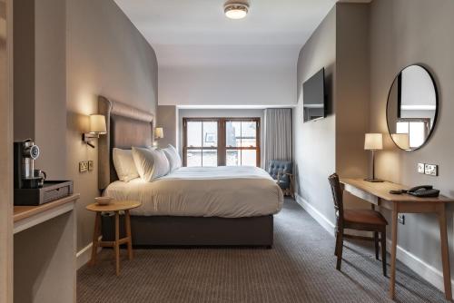 a hotel room with a bed and a desk and a mirror at Coachmans Townhouse Hotel in Kenmare