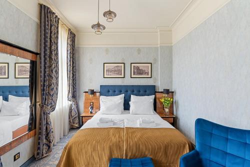 a bedroom with a bed and two blue chairs at Hotel Diament Plaza Katowice in Katowice