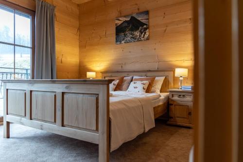 a bedroom with a bed with a wooden wall at Apartamenty Augustynówka in Brzegi