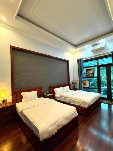 a bedroom with two beds and a large window at Cao Nguyên 2 Villa Hà Giang in Ha Giang