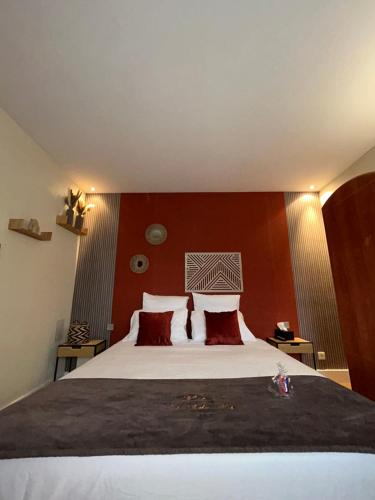 a bedroom with a large bed with red walls at Hôtel les Paturelles in Avesnelles