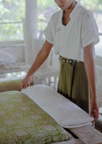 a woman is making a pillow on a bed at Trikora Beach Club and Resort in Telukbakau