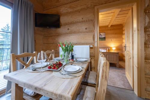 a dining room with a wooden table and chairs at Apartamenty Augustynówka in Brzegi