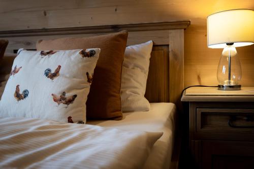 a bed with a pillow and a lamp on a table at Apartamenty Augustynówka in Brzegi
