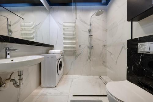 a bathroom with a sink and a washing machine at Golden Apartments Sokolska 30 Towers - Great Location&59 in Katowice