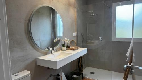 une salle de bain avec un lavabo et un miroir dans l'établissement Villa Casa Escorxada - A 150m de la playa de arena con piscina privada, à Santo Tomas