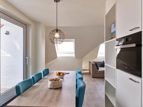 a kitchen and dining room with a table and blue chairs at Holiday Suites Zeebrugge in Zeebrugge