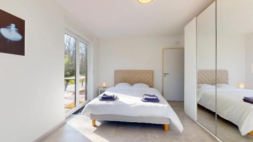 - une chambre blanche avec 2 lits et un miroir dans l'établissement Le Chalet avec Piscine - Obernai, à Obernai