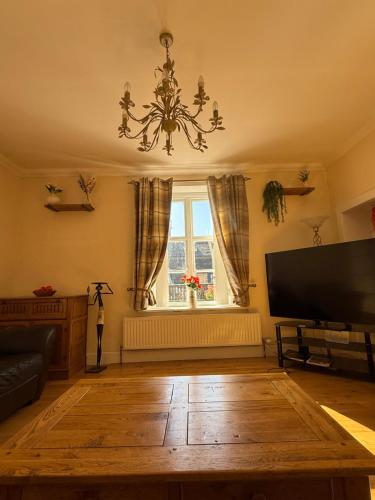 a living room with a television and a chandelier at Riverside Cottage City Centre in Inverness