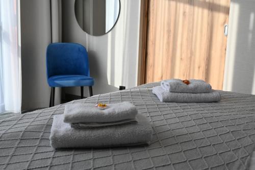 a bed with towels on top of it with a blue chair at Hotel Centrum Malbork in Malbork