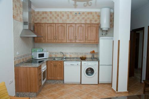 una cucina con armadi in legno, lavatrice e asciugatrice di Apartamentos Reysan a Vejer de la Frontera