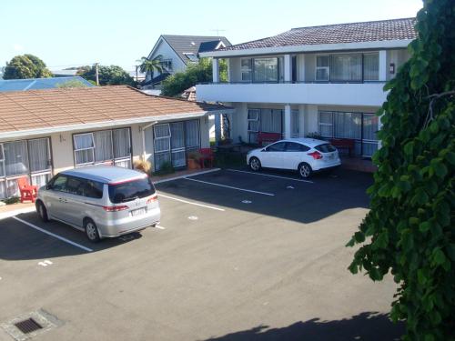 two cars parked in a parking lot in front of a building at Motel 22 in Lower Hutt