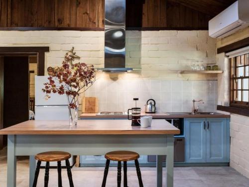 a kitchen with a table and two stools at Italian Hill Garden Villa in Daylesford