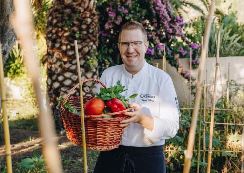 a man holding a basket of fruit and vegetables at Hotel Corsica & Spa Serena in Calvi