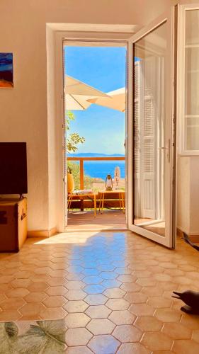 a room with a door open to a patio with the ocean at Solacargese Appartement de charme Vue imprenable Méditerranée in Cargèse