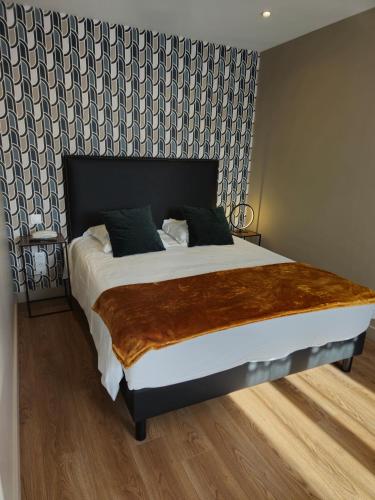 a bedroom with a large bed with a blanket on it at Le Beaugency in Beaugency