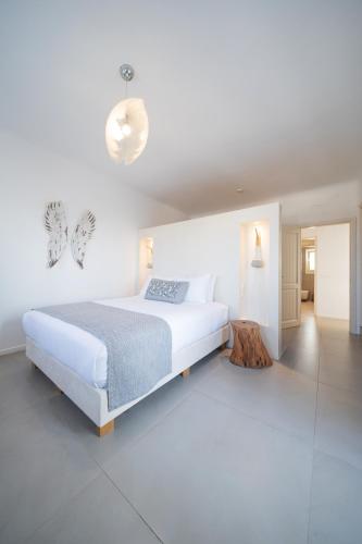 a white bedroom with a large bed and a table at White & Co Exclusive Island Villas in Pirgos