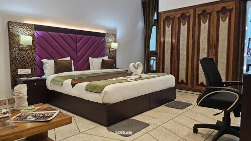 a bedroom with a large bed with a purple headboard at Solitude, The Boutique Hotel in Haldwāni