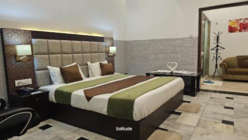 a bedroom with a large bed and a chair at Solitude, The Boutique Hotel in Haldwāni