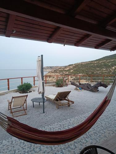 a hammock on a beach with chairs and an umbrella at Gavdos Panorama in Gavdos