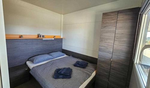 a bedroom with a bed with two blue pillows on it at Mobile Home Toni with shared pool near beach in Pirovac