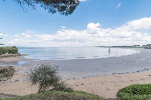 einen Strand mit einer Person, die im Wasser läuft in der Unterkunft La Mirmilly - 100m de la plage in La Plaine-sur-Mer