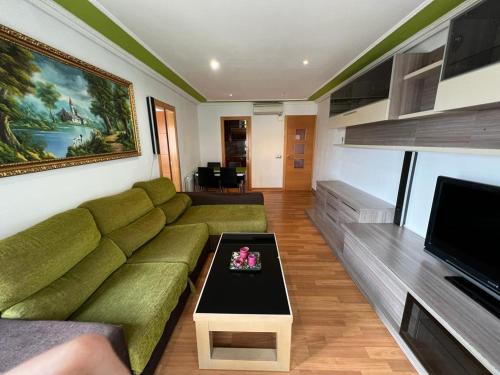 a living room with a green couch and a table at Bonito piso de 4 habitaciones- Port Aventura in Vila-seca