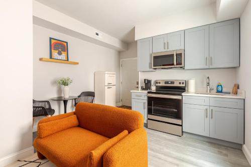 a living room with an orange chair in a kitchen at Philly Getaway - Chic Stay Near Center City in Philadelphia